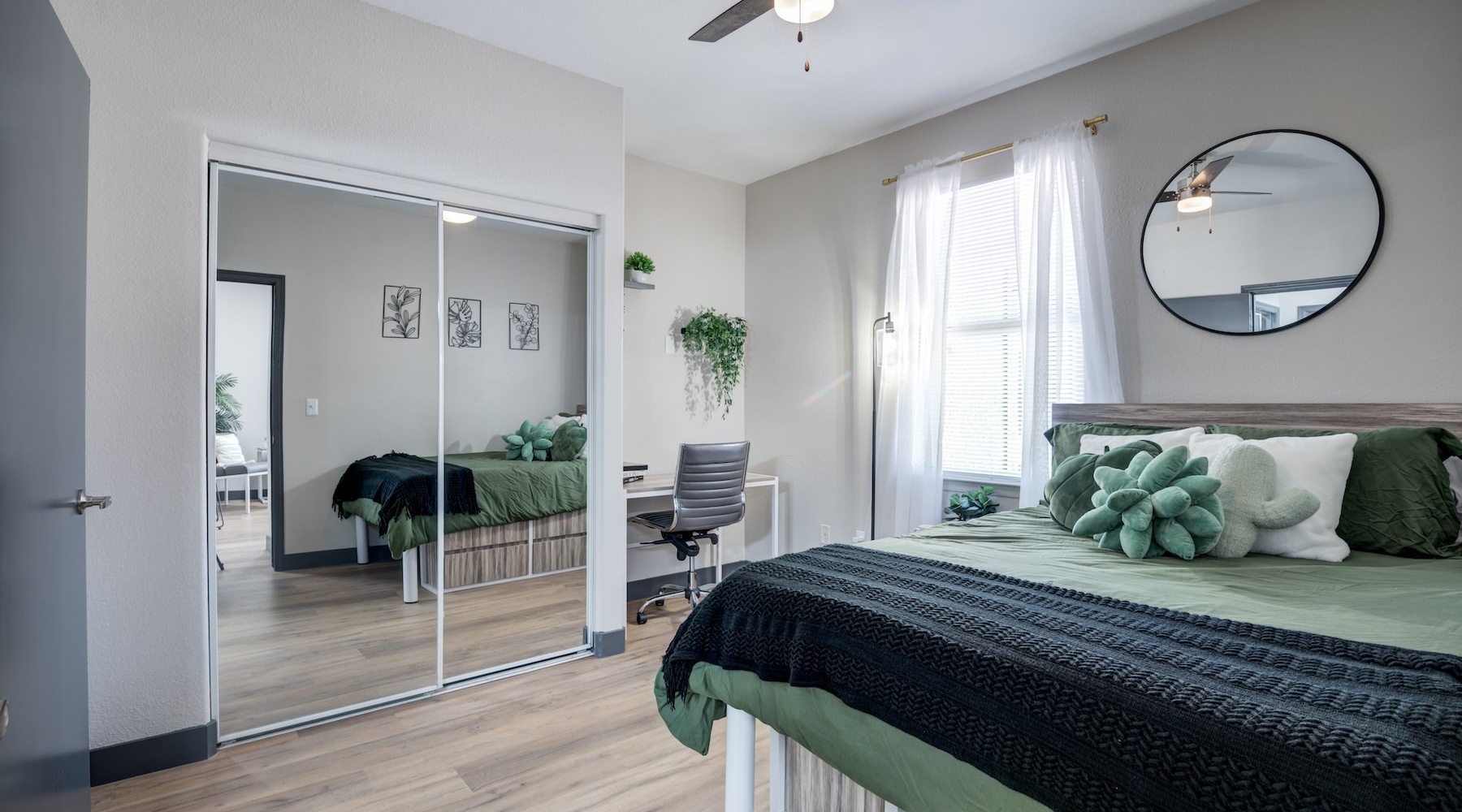 bedroom with bed mirrors ceiling fan and desk